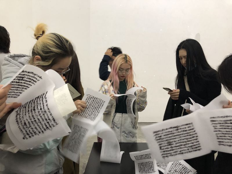 Gallery attendees reading the sexual abuse case in Lin‘s “Burn After Reading”