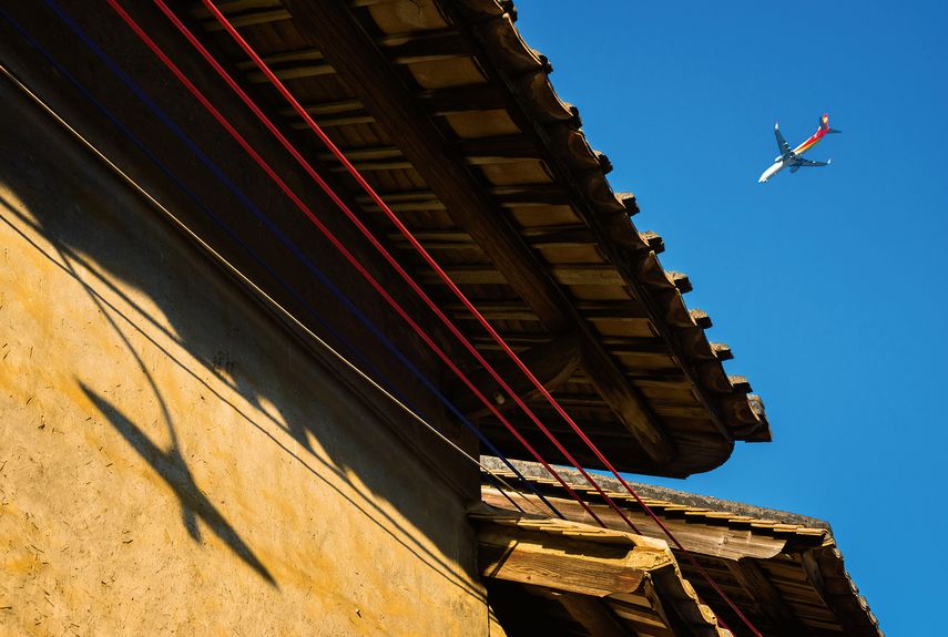 “Shadows on the Wall”: A plane’s reflection on an ancient dwelling contrasts the traditional and modern in China (Guangzhou, Guangdong Province, January 2019)