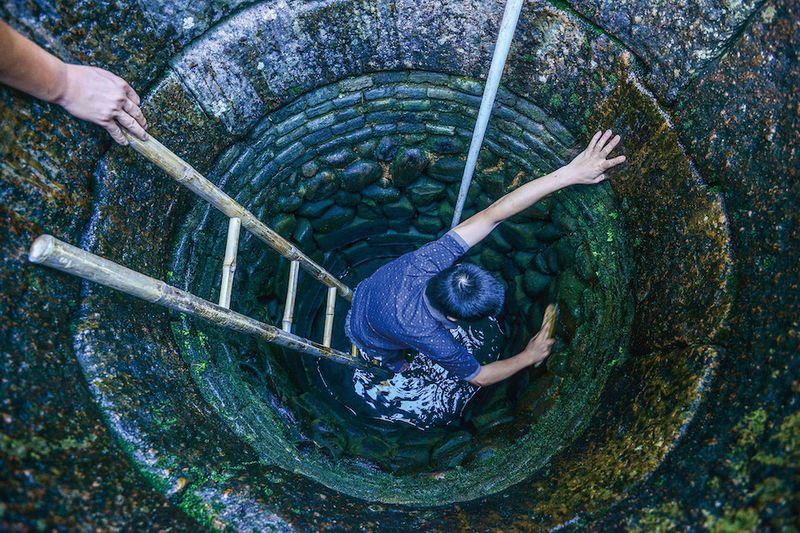 Villagers work together to drain the well, bucket by bucket