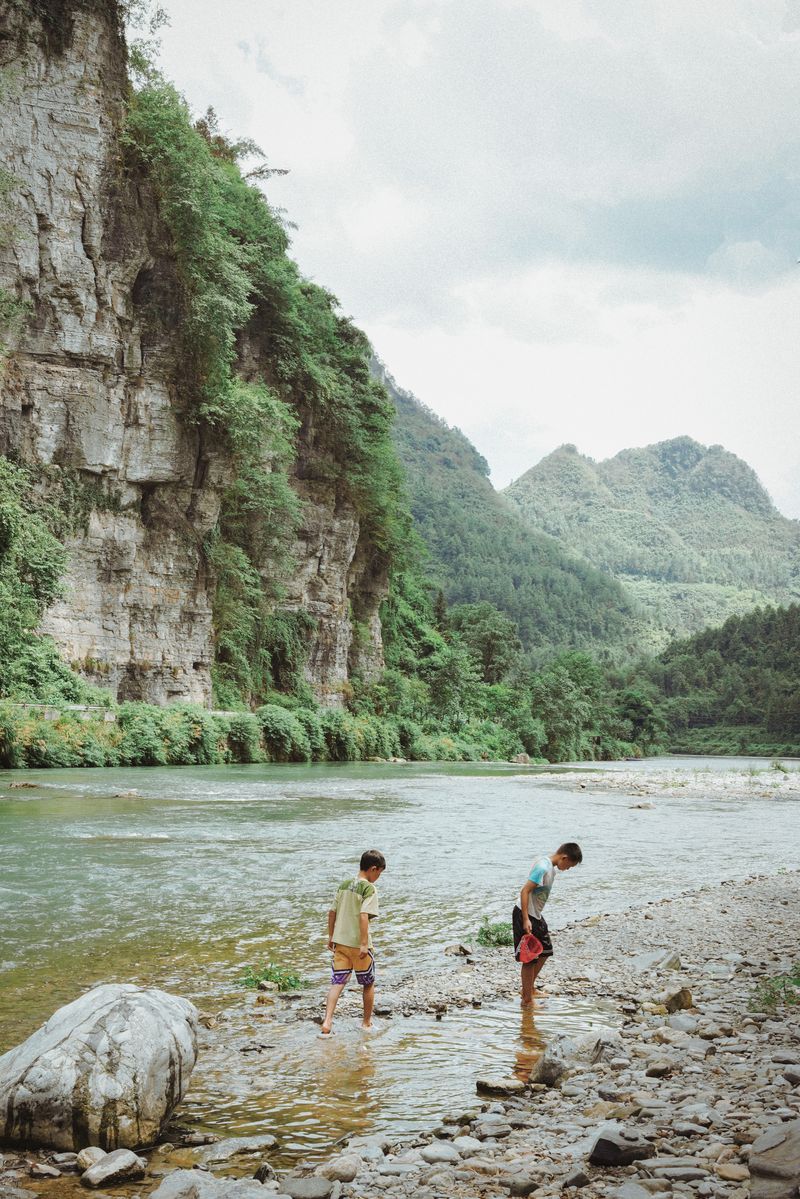 In summer, children catch fish in the river surrounded by the karst peaks of Huaihua, Hunan province