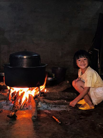 A Lahu girl cooks over a fire pit