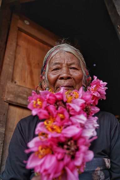 An elderly Wa woman wearing a fresh flower decoration