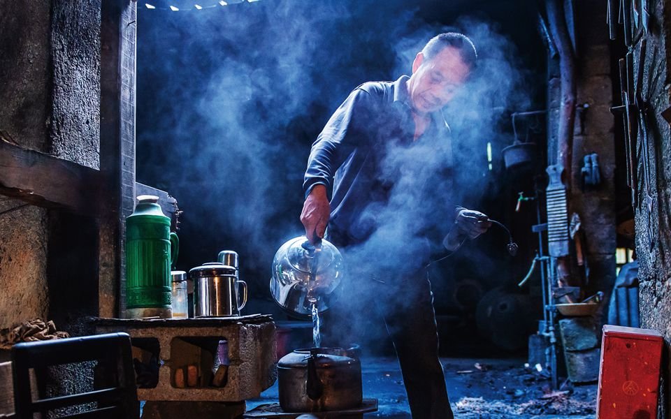 An employee pours hot water out in the while working at the Chinese wok factory, Molding a Chinese wok