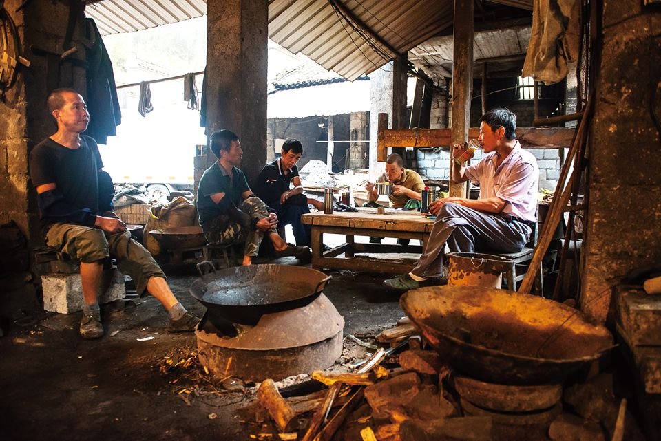 Chinese wok-making employees take a break and eat lunch.