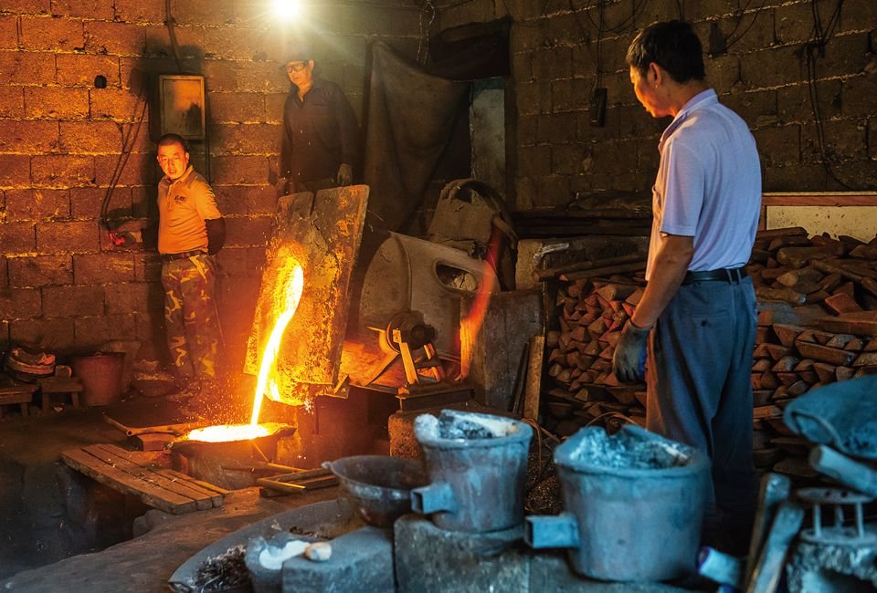 Factory workers carefully watch as molten iron is poured.