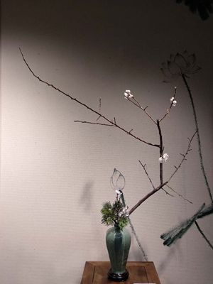 Chinese flower arrangement in round white flower vase against a grey wall