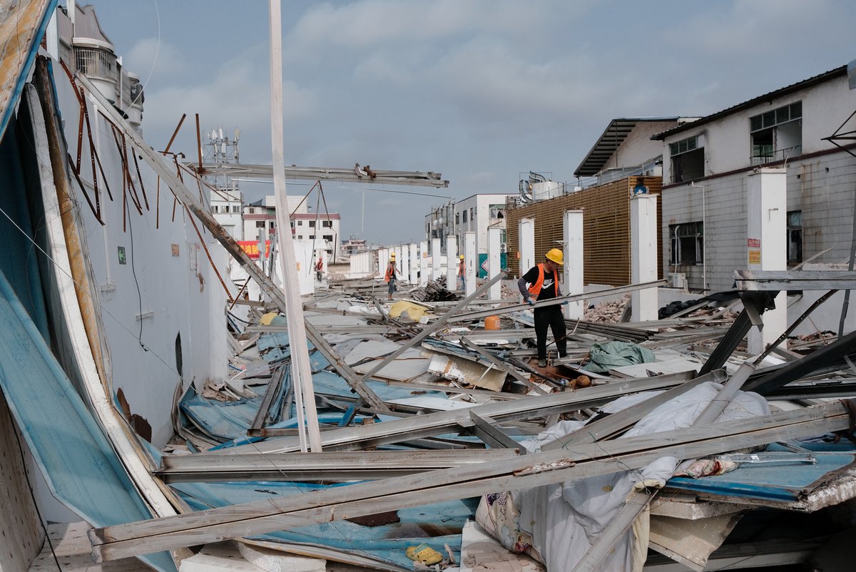 Workers demolish the factory on the rooftop in Lujiang village.