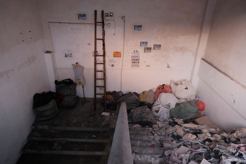 After the demolition of a rooftop factory, abandoned fabric and a mannequin are stacked in the stairs to the rooftop in Lujiang village, Guangzhou, June 10, 2023.
