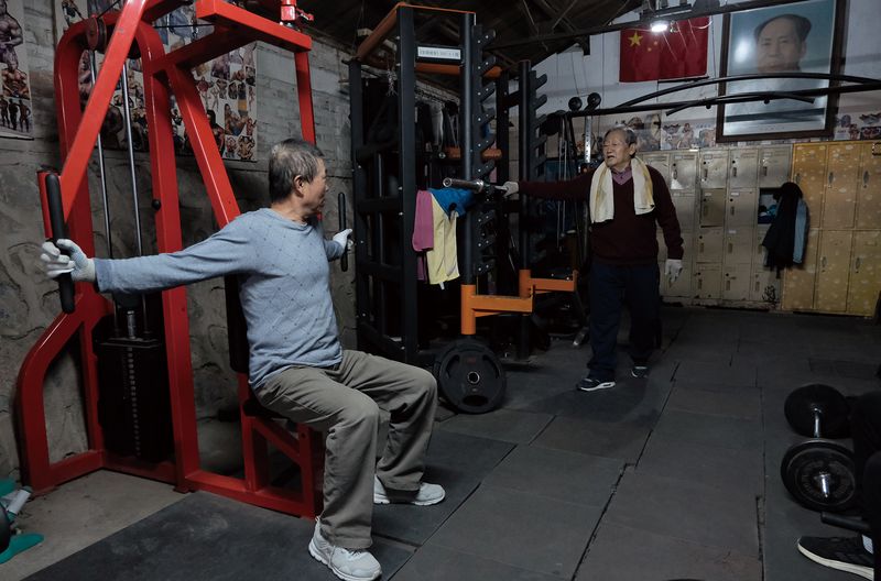 Yang Hongzeng (right), 84, talks to another senior working out. Yang is the oldest current member of the gym.