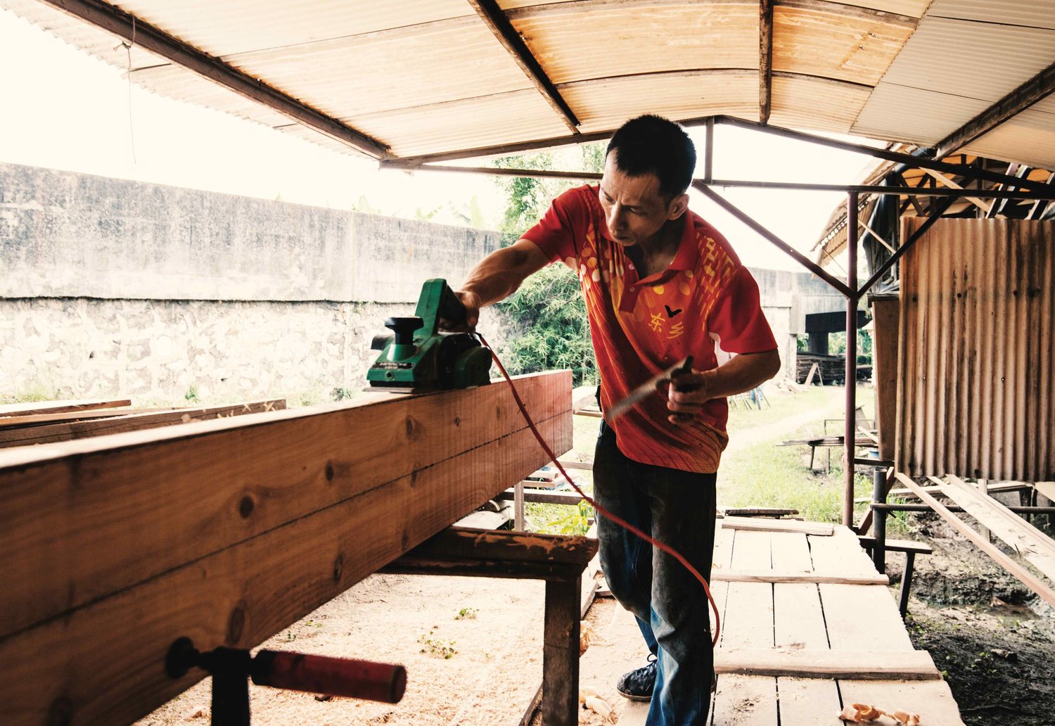 Guan Yongqiang cuts long strips of timber