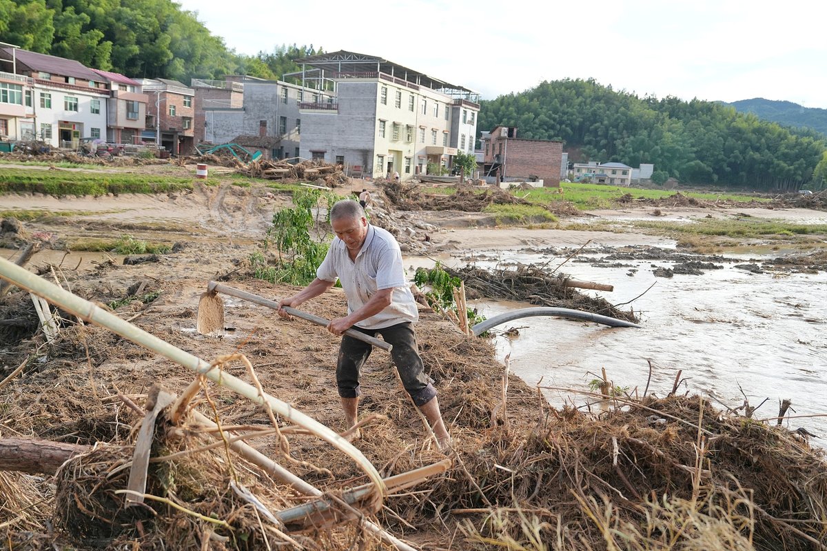 Chinese farmer in Zixing, Hunan going through wreckage from Typhoon Gaema