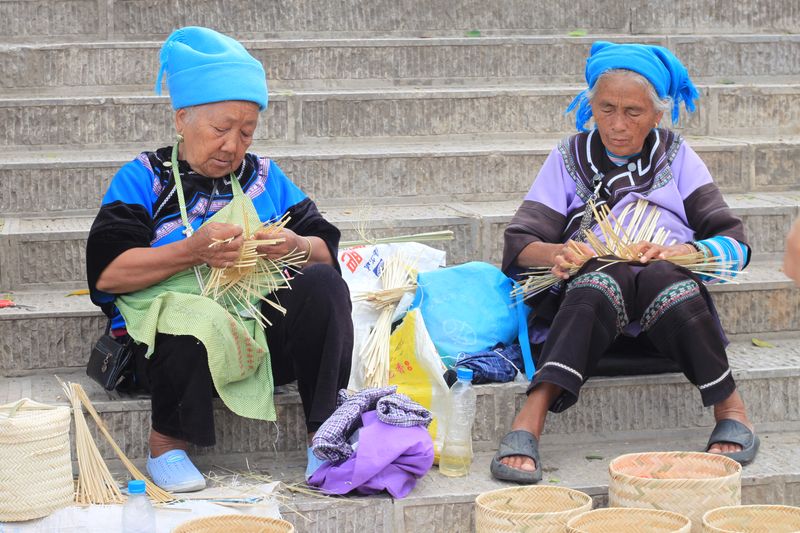 Two women from the Hani ethnic minority making baskets by the roadside