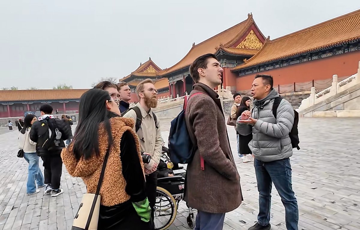 Foreign tourists listening to a Chinese tour guide while touring the Forbidden City, demand Chinese foreign language tour guides