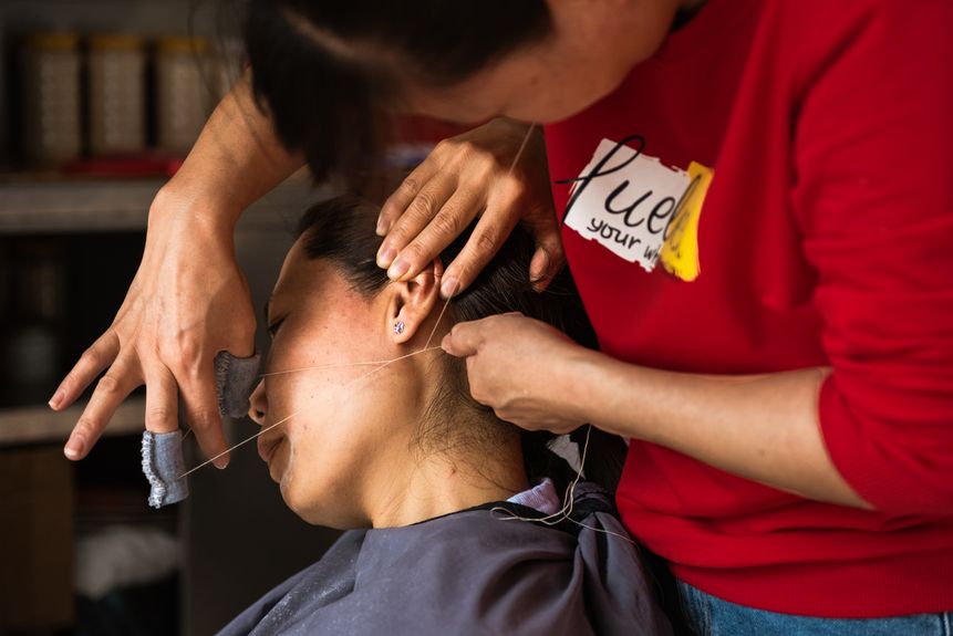 In the old district of Qingyuan City, Guangdong, a woman is getting her facial hair removed by a cotton thread, a traditional cosmetic skill to get ready for special occasions (2020)