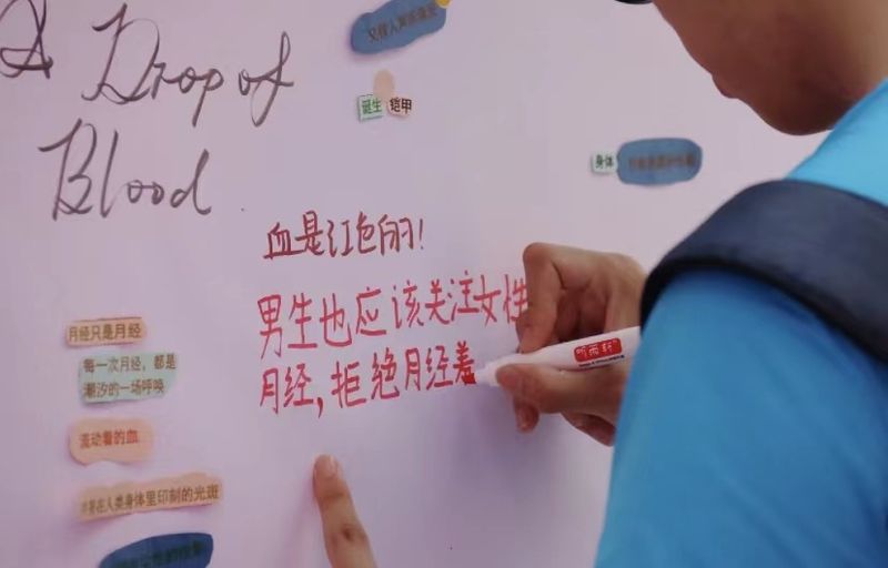 A male participant at Guangdong University of Foreign Studies’s period writing “Men should also pay attention to period. No period shaming” on the poster.