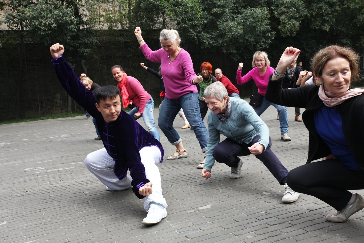 Chinese tour guide and foreign tourists practicing tai-chi