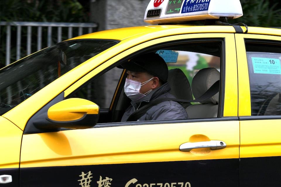 A taxi drivers sits in his yellow cab waiting for his next customer