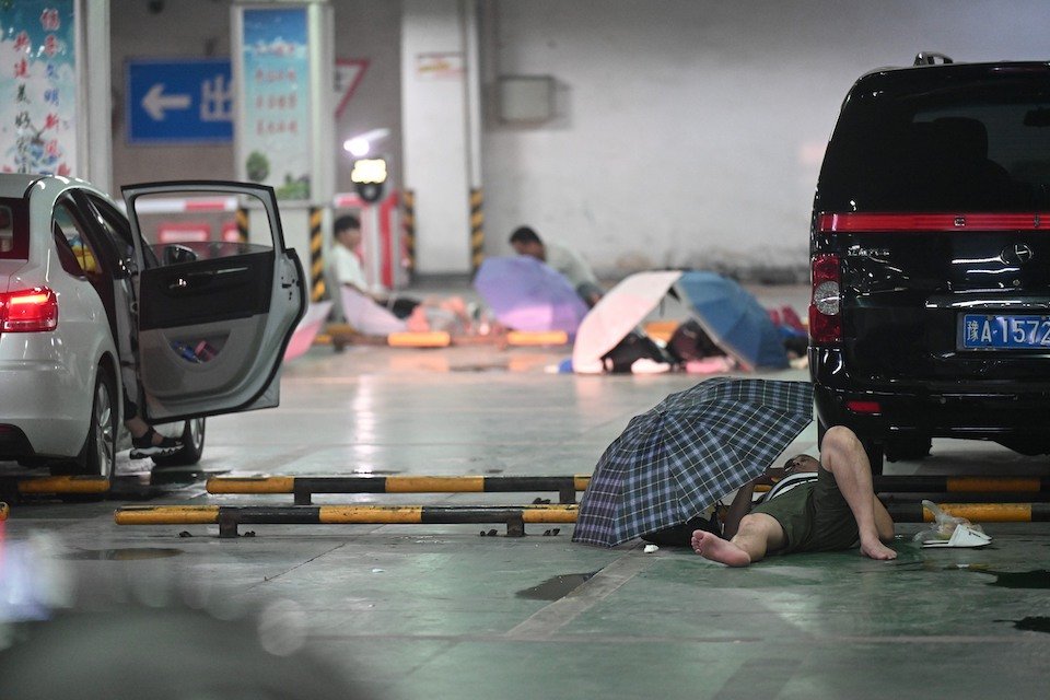 Residents take shelter in a parking lot avoid the rain and floods in Zhengzhou city (VCG)