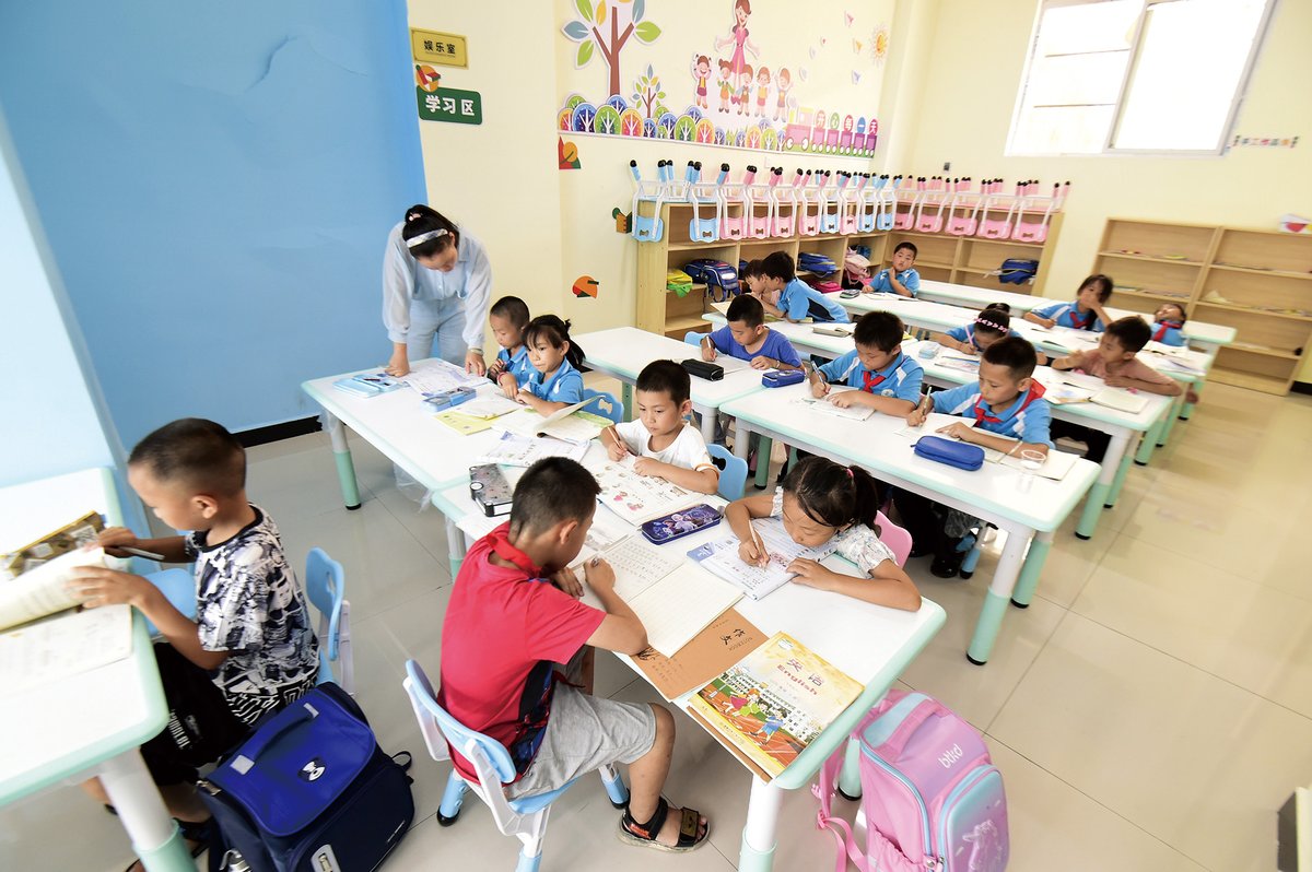 Children from a rural relocation program in Guizhou province doing homework in a community center, due to lack of parental care