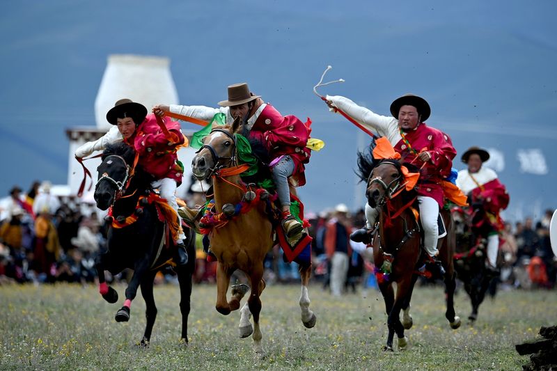 Three riders displaying traditional Tibetan horse-riding skills