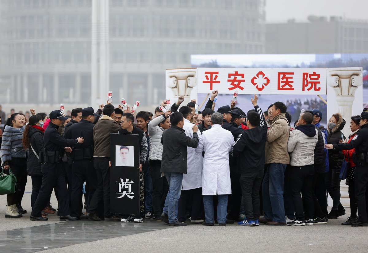 Policemen attempting to control a mob outside a hospital