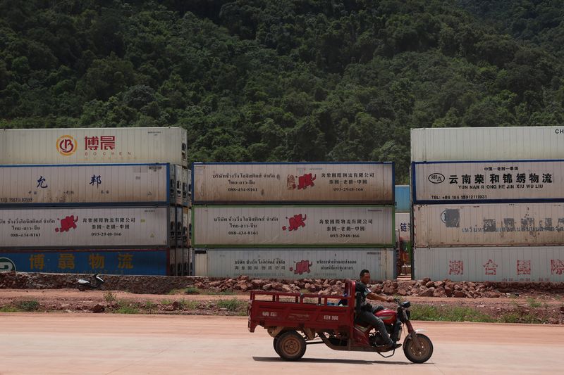 Stacks of cargo containers with Laotian and Chinese text sitting at the border in Boten