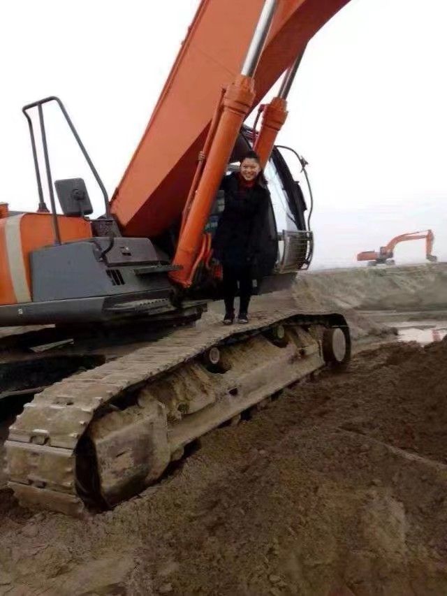 Wang Chunyan standing on top of an orange excavator