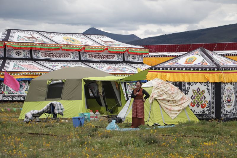 A tibetan woman stands in front of her tent near the horse racing site