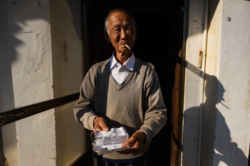 Huang Jichang with his slip of paper that claims his home was built in the early 18th century, tulou architecture