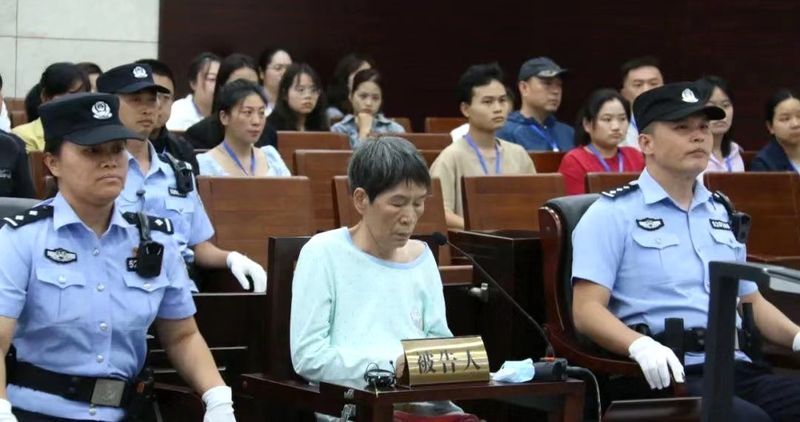 Yu Huaying sitting between two police officers showing little remorse throughout her court proceedings