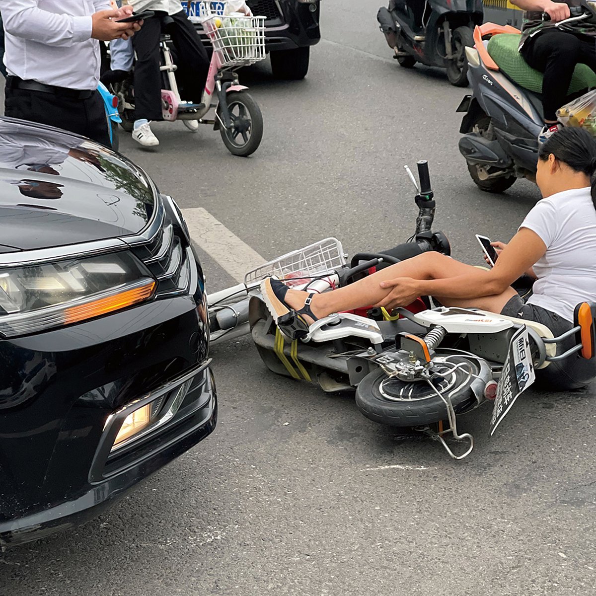 In the midst of a fender-bender, the scooter rider checks her phone in Lonely Planet