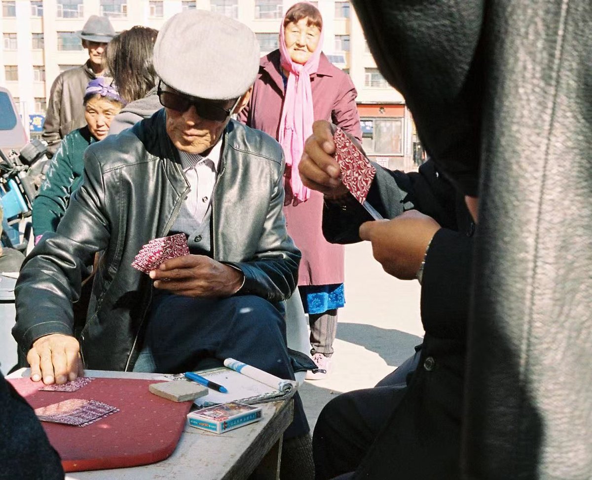 Retired herders playing cards near their apartments in Amugulang. Now they have no animals to look after they have lots of spare time.