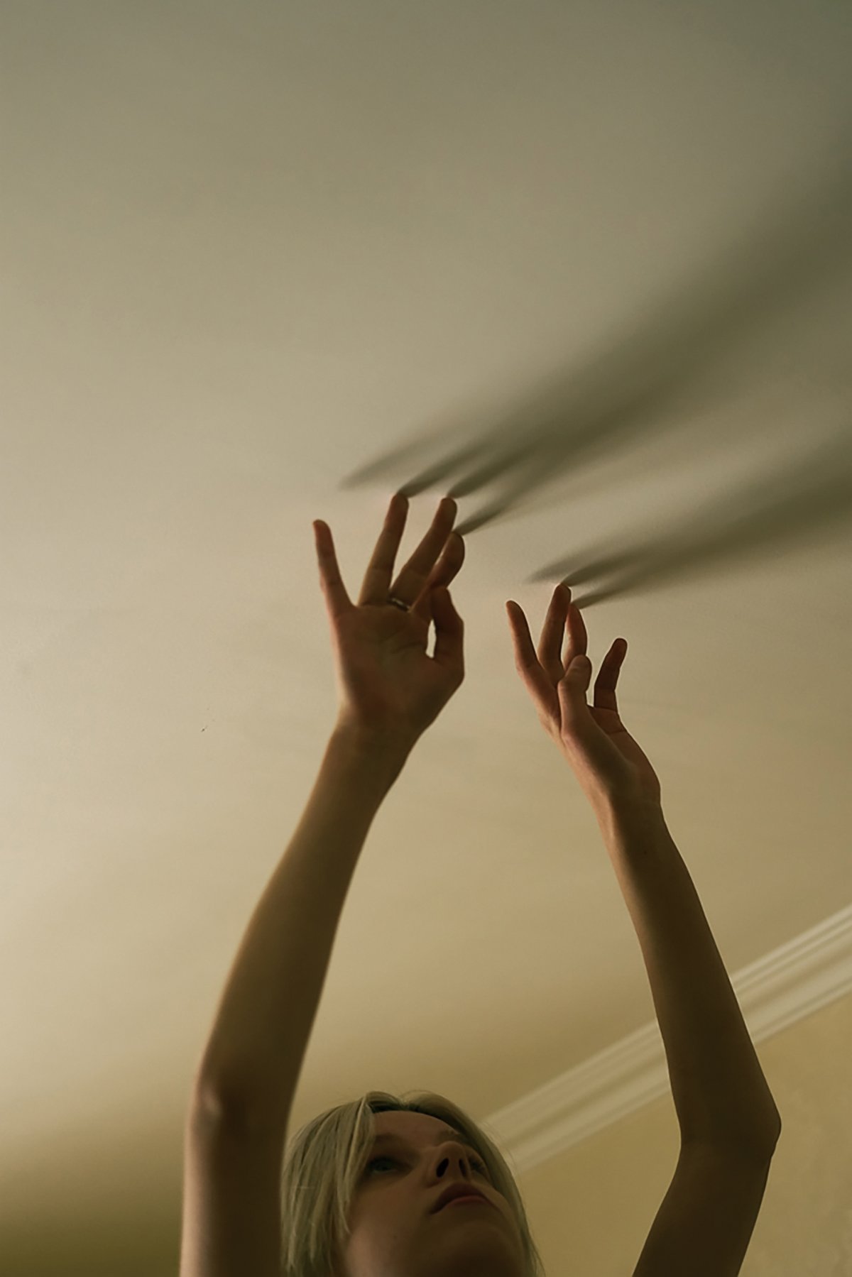 A woman playing with shadows on the ceiling, from Peking Apartments