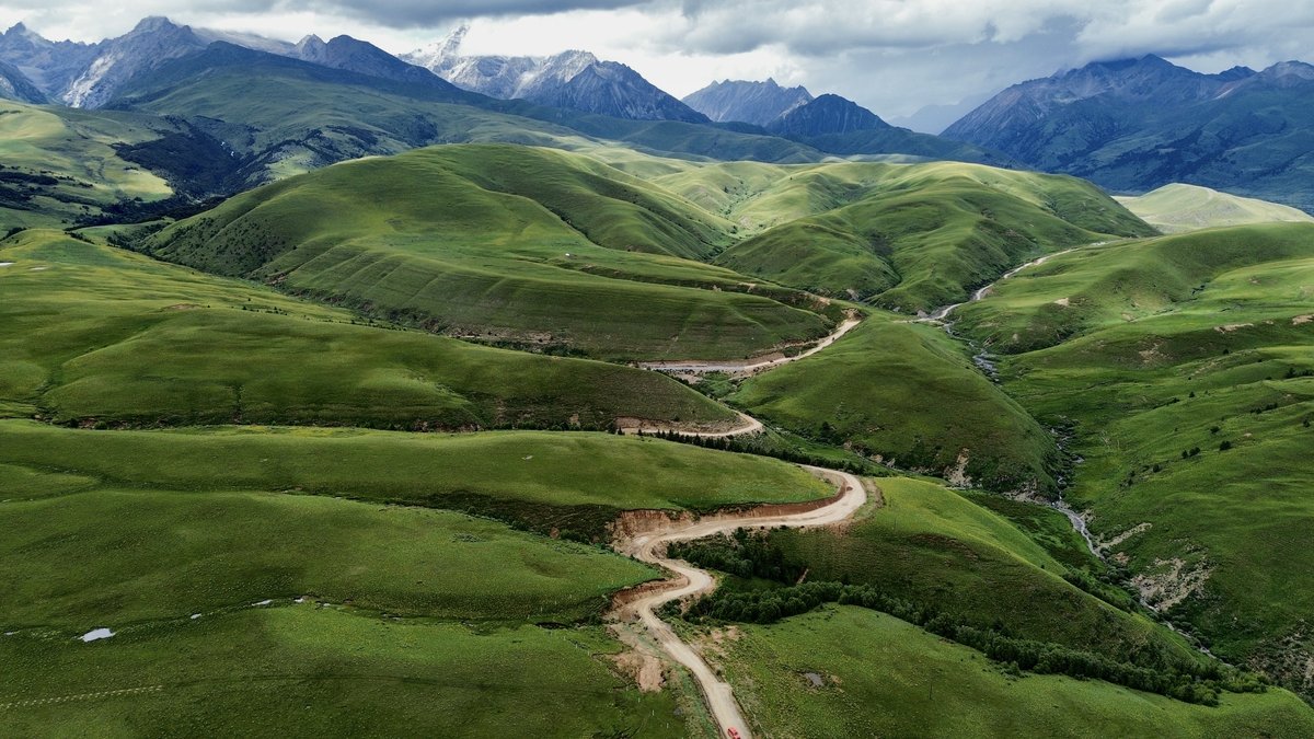 Green hilly lands near Litang extended all the way to far away snow mountains