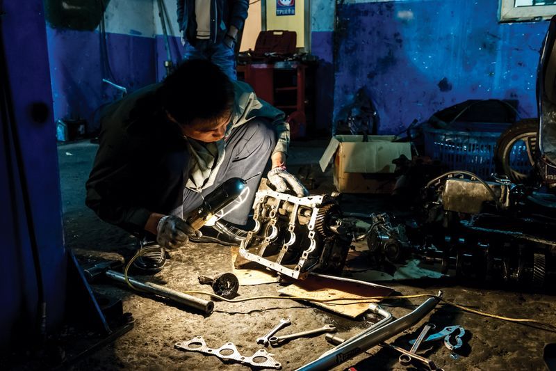 A mechanic puts the finishing touches on a paint job in the middle of the night