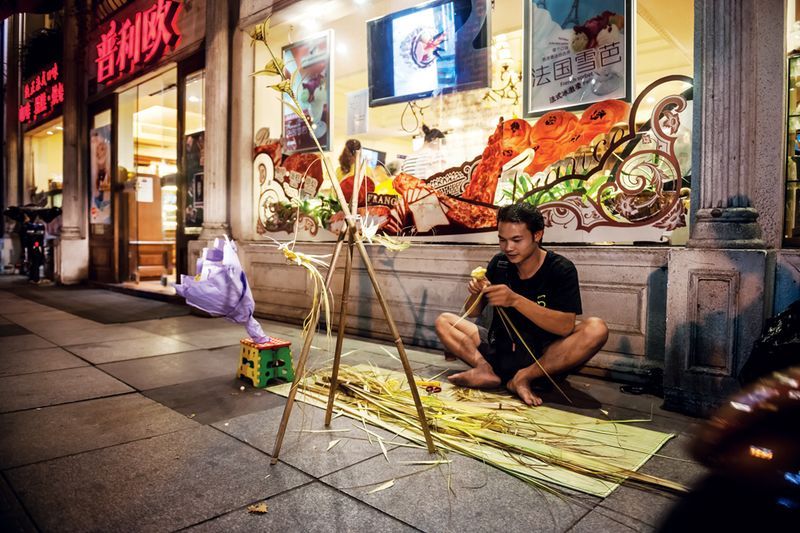 A craftsman, originally from Anhui province, weaves reeds into small knick-knacks to sell