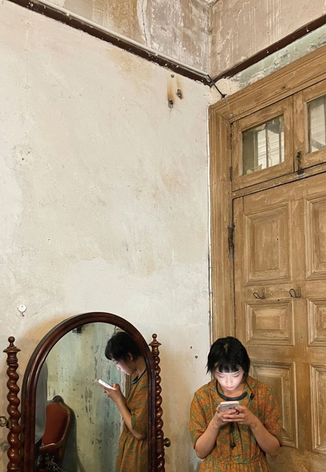 A woman and her smart phone are reflected in a mirror against a rustic backdrop in the Lonely Planet series